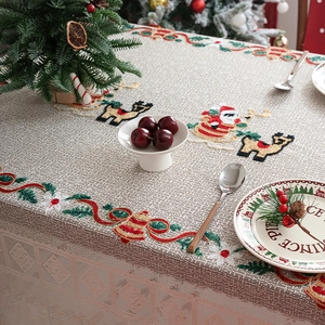 Detailed embroidery of Santa and reindeer on a beige holiday tablecloth runner