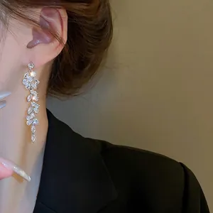 Elegant silver leaf tassel earrings with sparkling zircon crystals worn by a model