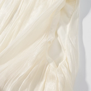 Close-up of pleated satin fabric texture with pearlescent sheen and side pocket detail