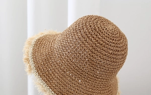 Detalle de un sombrero de paja marrón con bordes de flecos beige y textura
