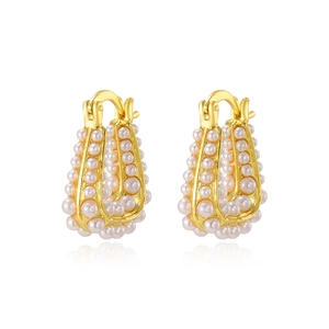 Boucles d'oreilles dorées rétro en forme de U avec perles sur fond blanc poli