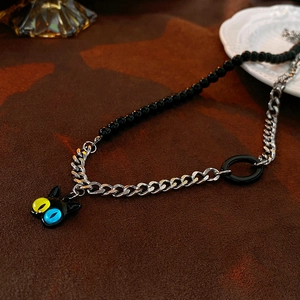 Detail of a punk acrylic cat necklace featuring asymmetrical black beads and silver chains