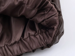 Detailed macro view of the elastic cuffs and fabric lining on brown faux leather jacket