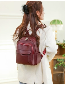 Detail of red PU leather backpack featuring metal rivet decor and adjustable shoulder strap