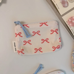 Detail of a mini cotton bag with red bow print and blue woven zipper pull strap