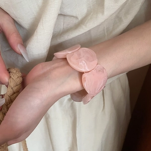 Detail of pink marble textured acrylic bracelet on wrist in a warm natural lifestyle setting