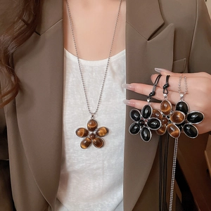 Detail of oval resin flower pendant necklace in brown and black on beaded and wax cords