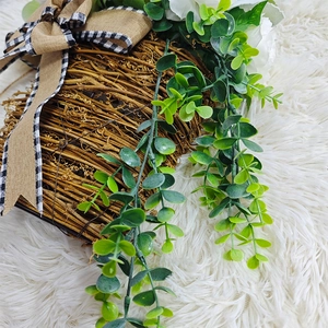 Close-up of white peony door basket with eucalyptus leaves and burlap plaid bow