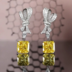 Radiant cut yellow diamond earrings with sparkling bow design and mirror reflection