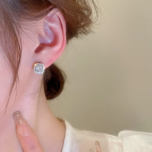 Close-up of a square silver earring with zircons worn on a model's earlobe