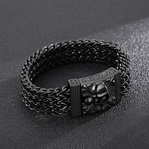 Macro view of black woven men's bracelet featuring a metallic skull clasp detail