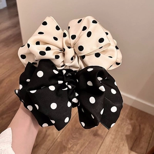 Detailed view of large polka dot satin bow hair clips in beige and black colors