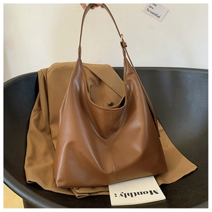 Detail of soft brown PU leather hobo bag with vertical stitching and wide strap