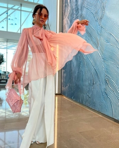 Detail of pink chiffon long sleeve shirt with tie neck and white wide-leg trousers