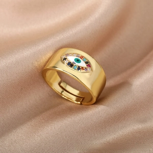 Macro shot of gold wide band evil eye ring with colorful zircons on satin fabric