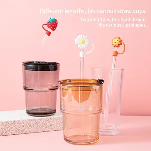 Cartoon silicone straw covers with strawberry and daisy designs on glass straws