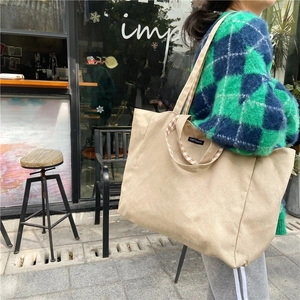 Detail of canvas tote bag featuring brown checkered lining on strap and brand tag