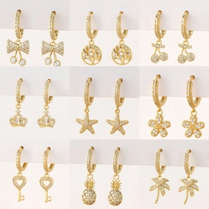 Collection of nine gold hoop earrings with zircon charms including bow and crown designs