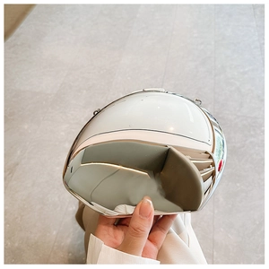 Macro detail of the oval acrylic clutch bag featuring a polished silver mirror finish