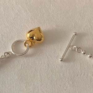 Detail of S925 silver beaded bracelet with gold heart charm and OT toggle closure