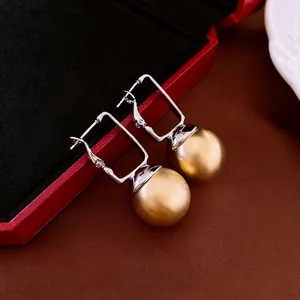 Modern square geometric earrings featuring matte gold sphere charms and silver needles