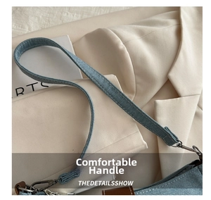 Close-up of denim shoulder bag featuring sturdy stitching and silver metal carabiner detail