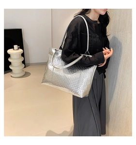 Silver woven tote bag worn by a model showcasing large capacity and metallic texture