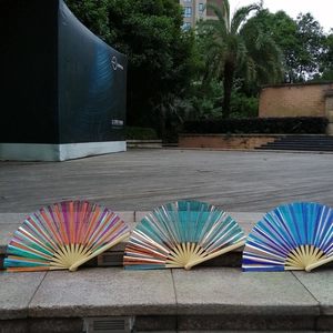 Close-up of three 33cm laser film bamboo fans in pink, green, and blue on stone steps
