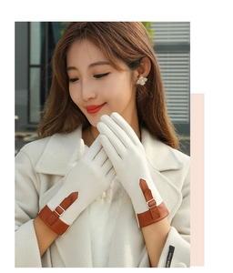 Detail of beige suede winter gloves featuring brown buckle strap and hand made label
