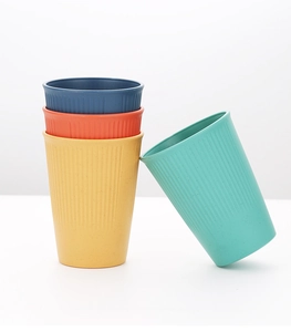 Close-up of four wheat straw cups in blue, red, yellow, and green with striped textures