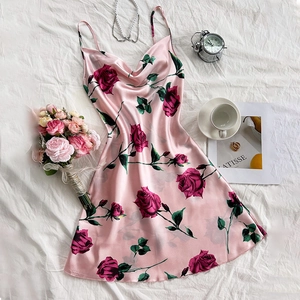 Pink satin floral slip dress with red rose print on white bedding, elegant summer style