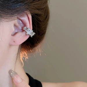 Close-up of silver star ear cuff with zircon crystals on female ear bone