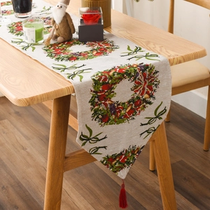 Detail of Christmas table runner with festive wreath pattern and red tassel accents