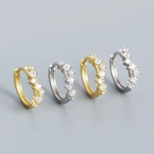 Close-up of geometric wave huggie earrings in gold and silver with sparkling crystals
