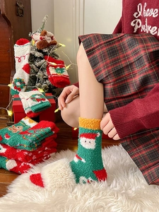 Detailed view of green coral fleece Christmas socks with Santa Claus pattern in cozy setting
