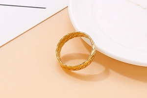 Dettaglio dell'anello dorato con texture a foglia e motivo a trama di spiga lucida