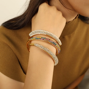 Three-row gold bangles with pearls and colorful zircons on a model's wrist