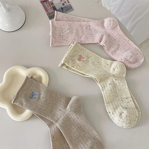 Detail of three pairs of speckled knit socks with embroidered bows and rolled cuffs