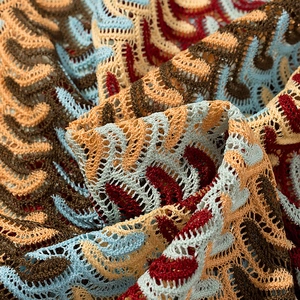 Gros plan sur la maille bohème avec des motifs ondulés colorés et des détails ajourés
