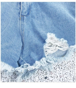 Dettaglio di pantaloncini di denim strappati con orlo sfrangiato e lavaggio azzurro
