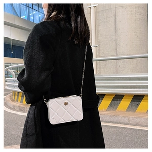 Detail shot of white quilted PVC jelly bag with gold chain strap on model's shoulder