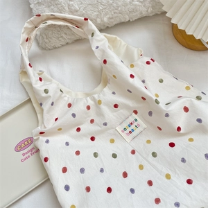 Détail du sac cabas en toile à pois colorés avec étiquette tissée de marque sur le devant