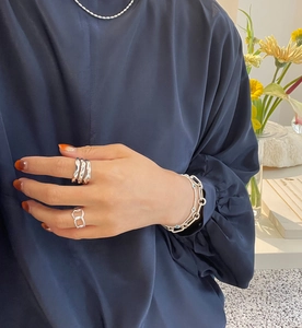Detail of layered S925 sterling silver rings and bracelets on elegant model hand