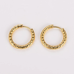 Macro detail of golden hoop earrings featuring a vintage hammered metal texture finish