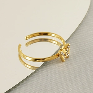 Macro shot of 18k gold butterfly ring with inlaid rhinestones on a mirror surface