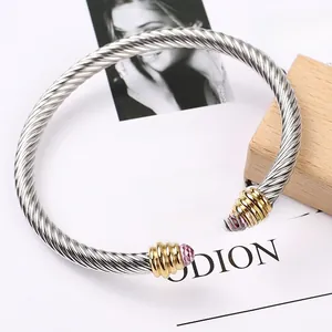 Detail of twisted cable steel bracelet featuring gold accents and pink crystal ends