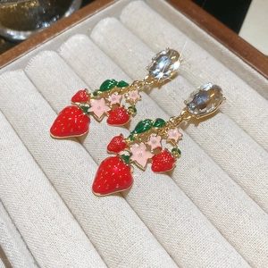 Detail of vintage strawberry earrings with red enamel and sparkling zircons on velvet