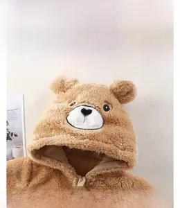 Détail macro d'une grenouillère bébé en peluche marron avec capuche ours et oreilles 3D