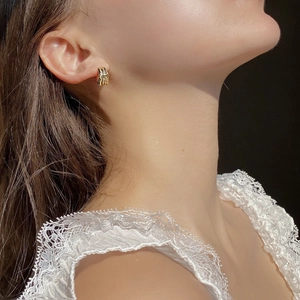 Close-up of elegant gold irregular textured earring worn by a model in soft lighting