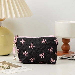 Quilted black cosmetic bag with pink bow print and large pearl charm accessory